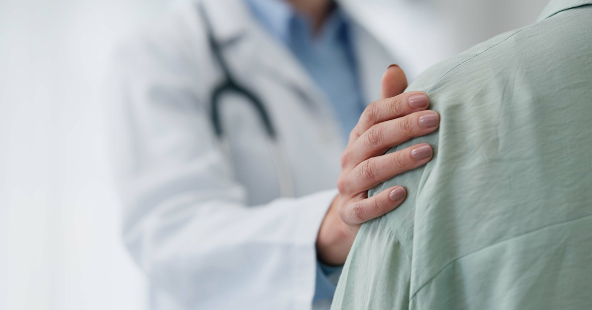 Doctor rests hand on a patient's shoulder. 