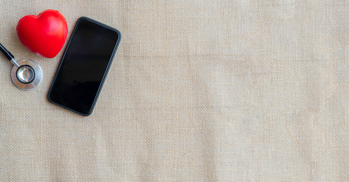 A phone next to a heart and stethoscope. 